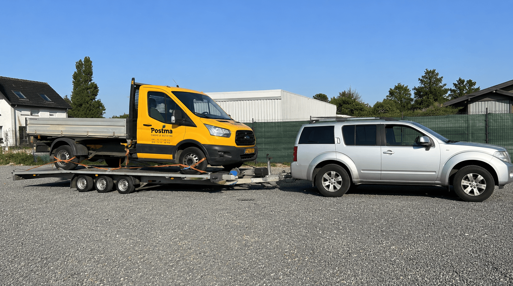 Abschleppwagen transportiert einen Transporter auf einem Tieflader bei Tageslicht